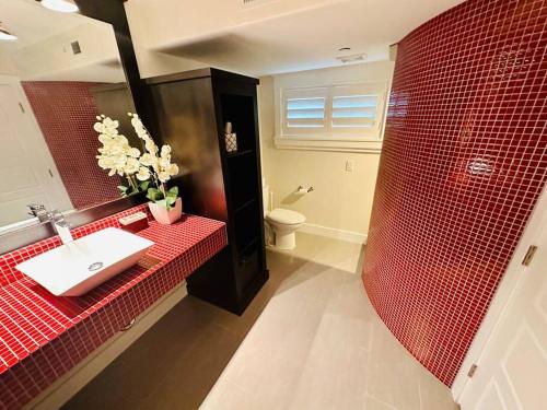 baño con lavabo y pared de azulejos rojos en Hobbs Creek, en Layton