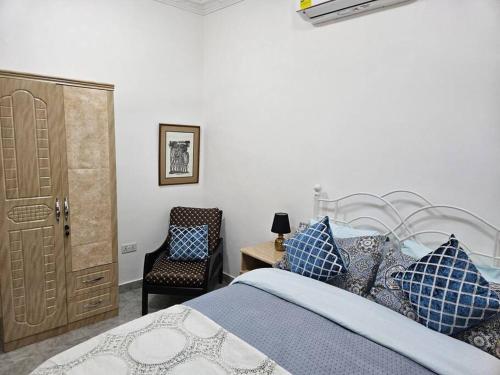 ein Schlafzimmer mit einem Bett mit blauen Kissen und einem Stuhl in der Unterkunft Gardens Apartment in Accra