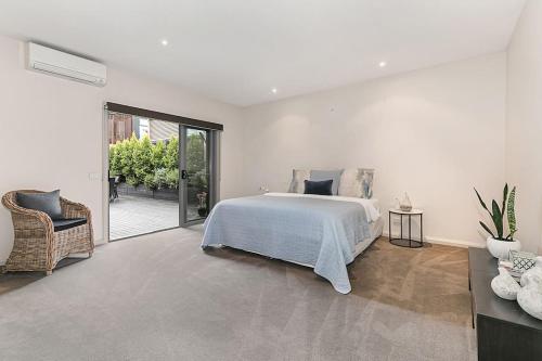 Un dormitorio blanco con una cama y una silla. en On The Bay Blairgowrie, en Blairgowrie