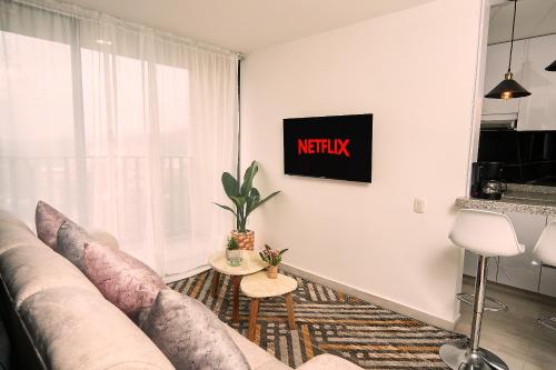 sala de estar con sofá y TV en la pared en Habitación premium sede 2, en Ibagué