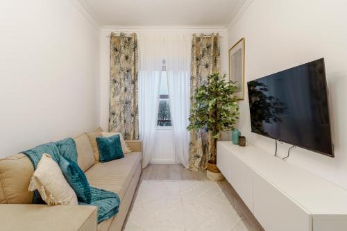 a living room with a couch and a flat screen tv at Apartamento Goa in Amadora