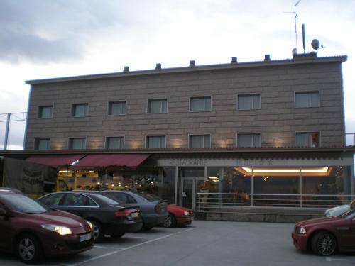 a building with cars parked in a parking lot at Hotel San Cibrao in San Ciprián de Viñas