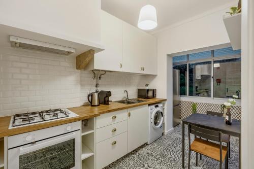 a kitchen with a stove top oven next to a washing machine at Apartamento Goa in Amadora