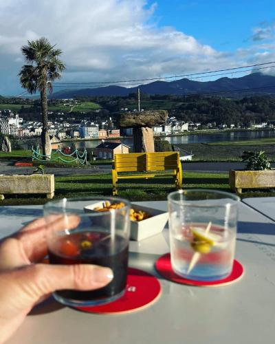 a person holding two glasses of drinks on a table at Hotel Capellan in Navia