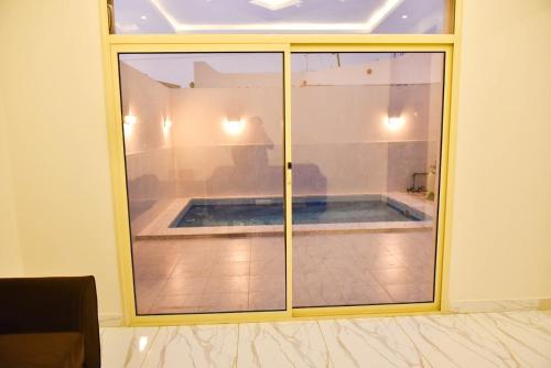 - une vue sur la piscine par une porte en verre dans l'établissement بيوت عطلات دور المصيف للضيافة السياحي, à Qarār