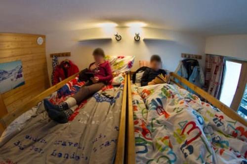 dwoje dzieci siedzących na łóżku piętrowym w obiekcie Les Menuires coeur de station w Les Menuires