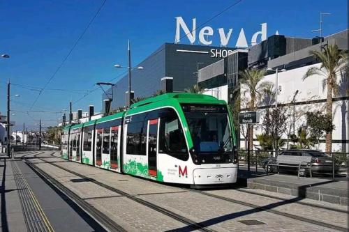 a green and white tram on a city street at Acogedor piso a un paso de Granada Capital. in Granada