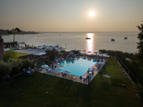 a group of people standing around a swimming pool near the water at Hotel Marolda in Sirmione