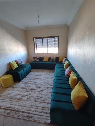 a living room with a green couch and yellow pillows at Appartement Cozy Louizia in Ben Yakhlef