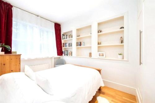 2 Betten in einem weißen Schlafzimmer mit Fenster in der Unterkunft Neat, bright, and convenient. in London