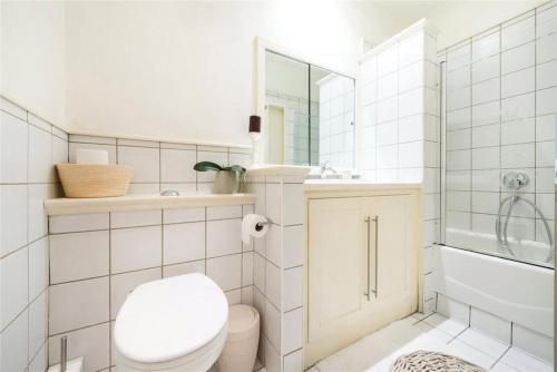 a white bathroom with a toilet and a shower at Neat, bright, and convenient. in London