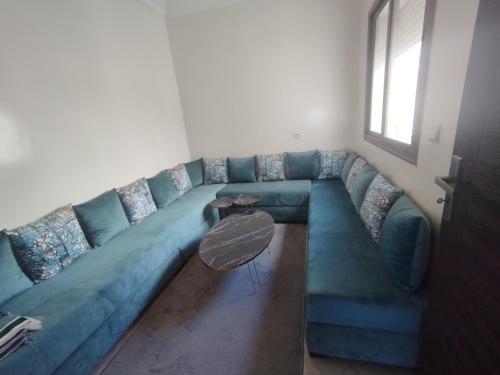 un divano blu in soggiorno con tavolo di Appartement Cozy Louizia a Ben Yakhlef
