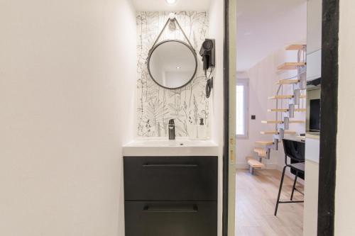 une salle de bain avec un lavabo et un miroir sur un mur dans l'établissement Tiny-duplex, à Lyon