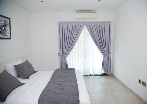 ein Schlafzimmer mit einem Bett und einem großen Fenster in der Unterkunft Yenko Fie Suites: The Signature Apartments, Accra Ghana in Accra