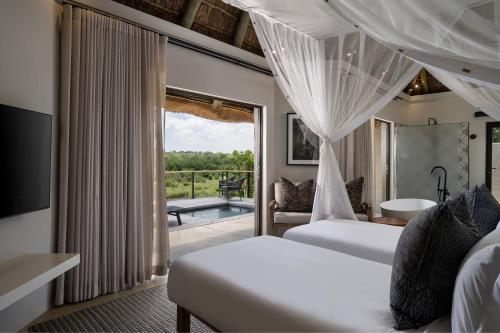 a hotel room with two beds and a balcony at Leopard Sands Kruger Park in Skukuza