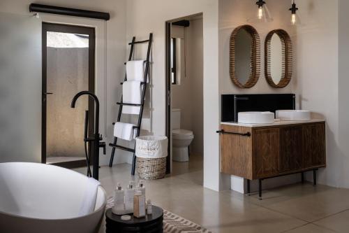 ein Badezimmer mit einer Badewanne, einem Waschbecken und Spiegeln in der Unterkunft Leopard Sands Kruger Park in Skukuza