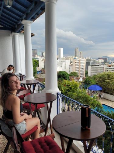 a woman sitting at tables on a balcony with a view at Hostel Sunrise in Rio de Janeiro
