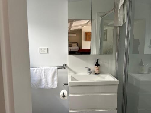 a white bathroom with a sink and a mirror at Shazza’s Desert Oasis in Broken Hill