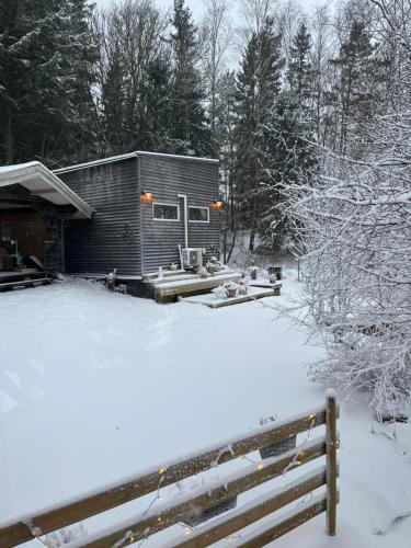 a small cabin in the snow with a fence at 15 min från Ullared! Ny stuga med hög standard! in Älvsered