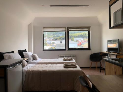 ein Schlafzimmer mit einem großen Bett und zwei Fenstern in der Unterkunft Al fin un mundo in Ushuaia