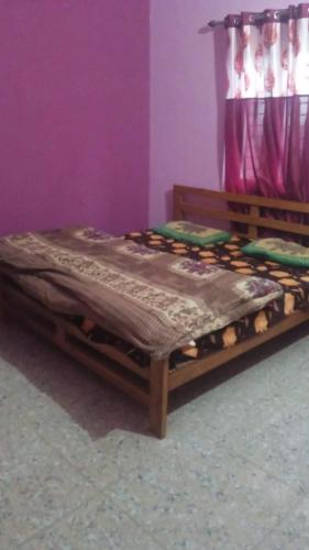 Cama de madera en habitación con pared morada en Garvita home stay, en Belparāo