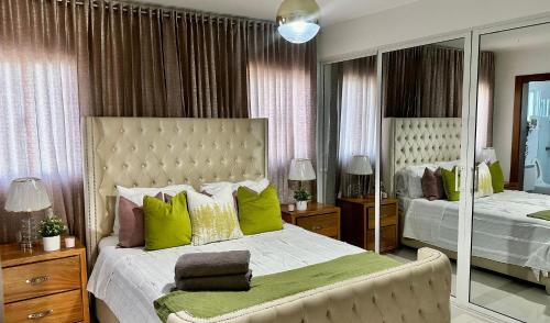 een slaapkamer met een groot bed met groene kussens bij Family Fun Vacation In Paradise in Santiago de los Caballeros