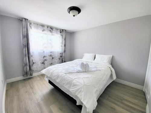 Schlafzimmer mit einem Bett mit weißer Bettwäsche und einem Fenster in der Unterkunft Cozy Home Close to Attractions in Niagara Falls in Thorold