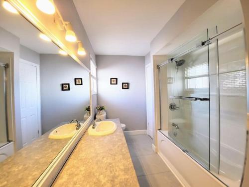 a bathroom with a shower and two sinks and a glass shower stall at Cozy Home Close to Attractions in Niagara Falls in Thorold