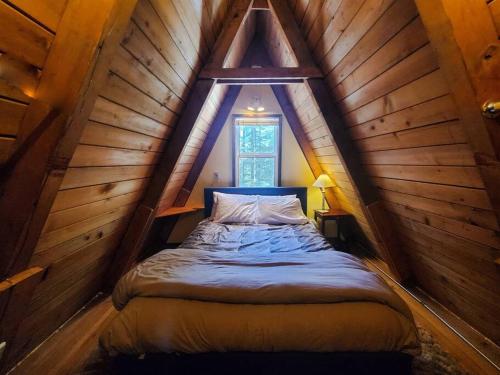 ein Schlafzimmer mit einem Bett im hölzernen Dachgeschoss in der Unterkunft Douglas Island A-frame Cabin in the Woods in Juneau