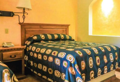 a bedroom with a bed and a table with a phone at Hacienda Suites Loreto in Loreto