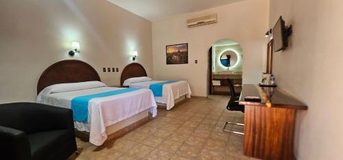 Habitación de hotel con 2 camas y espejo en Hacienda Suites Loreto en Loreto