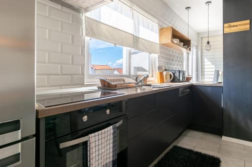 a kitchen with black cabinets and a sink and a window at Villa Radić in Makarska