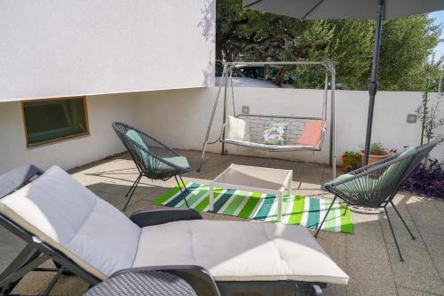 a patio with a swing and chairs and an umbrella at Villa Radić in Makarska