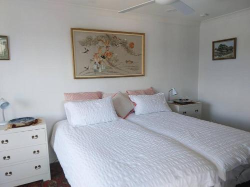 a bedroom with a bed and a picture on the wall at Chic 2 Bed, 2 Bath Retreat in Burleigh Waters in Gold Coast