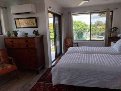 - une chambre avec un lit, une commode et des fenêtres dans l'établissement Chic 2 Bed, 2 Bath Retreat in Burleigh Waters, à Gold Coast