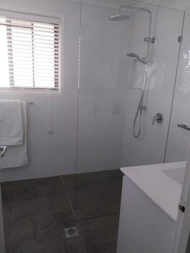 La salle de bains blanche est pourvue d'une douche et d'un lavabo. dans l'établissement Chic 2 Bed, 2 Bath Retreat in Burleigh Waters, à Gold Coast
