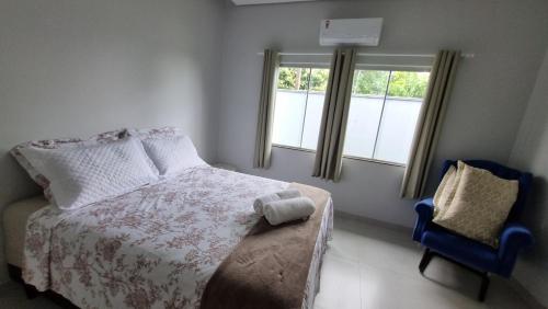 a bedroom with a bed and a chair and a window at Casa Nova com Suíte! in Sinop