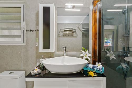 La salle de bains est pourvue d'un lavabo blanc et d'une douche. dans l'établissement Fare Oaoa Haapiti, à Moorea
