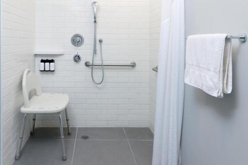 a white bathroom with a shower and a chair at avid hotels - Tijuana - Otay by IHG in Tijuana