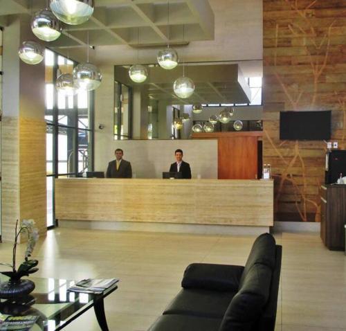 two men sitting at a reception desk in a lobby at Flat confortável e econômico hotel condomínio cristal place in Goiânia