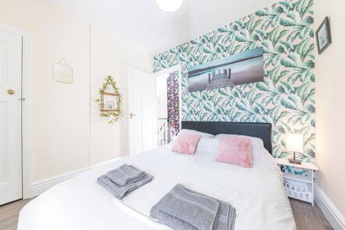 um quarto com uma grande cama branca com almofadas cor-de-rosa em Charming cottage, Lake District em Little Broughton