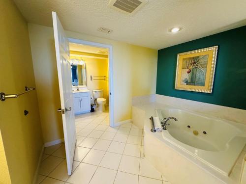 a bathroom with a white tub and a green wall at Club Wyndham Ocean Walk in Daytona Beach