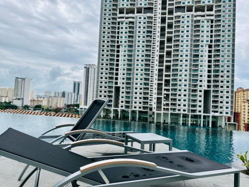 a pool with chairs and a table and a building at New 2BR or 3BR Homey Getaway stay 7 to 10 pax at Urban Suites, Georgetown by URBAN STAYCATION LOD in Jelutong