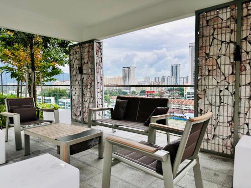 a balcony with chairs and a table and a couch at New 2BR or 3BR Homey Getaway at Urban Suites, Georgetown 7 to 10pax in Jelutong