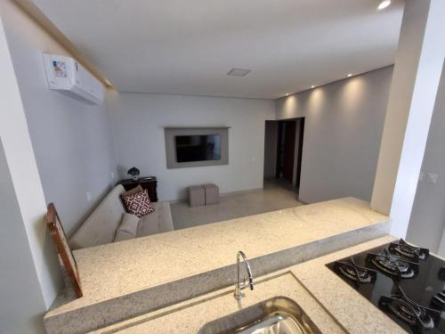 uma cozinha com um lavatório e um fogão e uma sala de estar em Casa Nova com Suíte! em Sinop