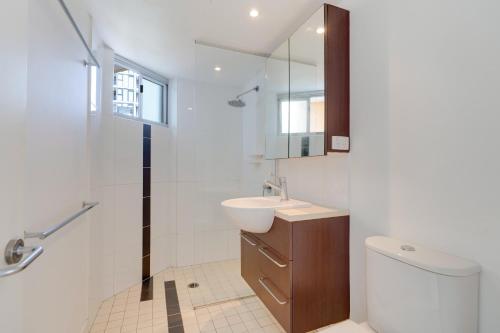 a bathroom with a sink and a toilet and a mirror at Urban 2BR Gem: City Chic Retreat in Brisbane