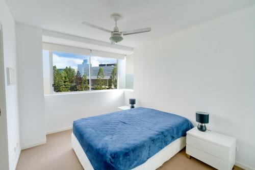 a white bedroom with a blue bed and a window at Urban 2BR Gem: City Chic Retreat in Brisbane