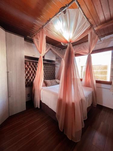 Schlafzimmer mit Himmelbett und Vorhängen in der Unterkunft Magic house banheira de hidromassagem e piscina in Rio Grande