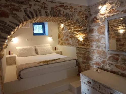 1875 panoramic stone house في Filótion: غرفة نوم بسرير وجدار حجري