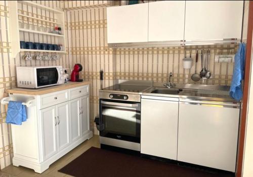 a kitchen with white cabinets and a stove and a microwave at CASA VACANZA NIDO COLLETTO in Case Arfel